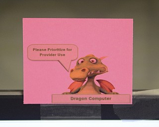 Katie Rickman | The Vindicator.A photo of a dragon is taped to the top of a computer with the Dragon medical program that dictates notes for him into a computer at St. Joseph's in Warren on May 5, 2015.