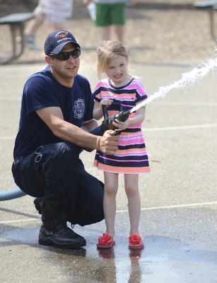 Katie Rickman | The Vindicator.Ava Hunt 5 of Beloit grimaces as she concentrates on knocking down cardboard flames from a house-like frame, Capt. Cory Palmer of Damascus Fire and Rescue assists her at the 5th annual Carnival  at Damascus Elementary School on May 9, 2015.
