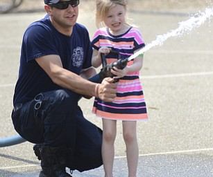 Katie Rickman | The Vindicator.Ava Hunt 5 of Beloit grimaces as she concentrates on knocking down cardboard flames from a house-like frame, Capt. Cory Palmer of Damascus Fire and Rescue assists her at the 5th annual Carnival  at Damascus Elementary School on May 9, 2015.