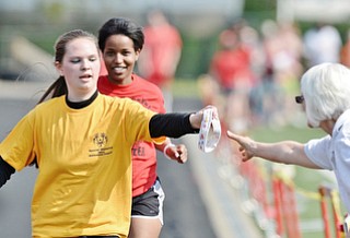 Jeff Lange | The Vindicator  MAY 9, 2015 - Ashtabula's Tiffany Pelton (left) hands off her head band during her run in the 1,500 meter run during Saturday's Special Olympics in Girard.