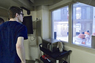 Jeff Lange | The Vindicator  MAY 7, 2015 - Jackson Milton senior Jacob Lattimer (left) peers through a window at inmates seated around a small television, Thursday morning at the Mahoning County Jail in downtown Youngstown.