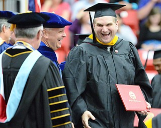 Jeff Lange | The Vindicator  MAY 16, 2015 - Patrick Peachock (right) shares a moment of laughter with the trustees as he walks across the stage after receiving his masters in Business Administration, Saturday morning during the commencement ceremony at YSU.