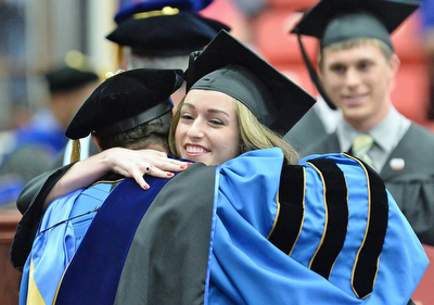 Jeff Lange | The Vindicator  MAY 16, 2015 - Ashley Bowers embraces one of the trustees after accepting her bachelors degree in engineering during Saturday morning's commencement ceremony at YSU.