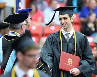 Jeff Lange | The Vindicator  MAY 16, 2015 - Cameron Dimopoulos, age 19 (right) smiles at YSU President Jim Tressel as he walks across the stage after receiving his bachelors degree in computer science during Saturday morning's commencement ceremony at the Beeghly Center. Dimopoulos, a 2013 graduate of Poland High School earned his four-year degree in two years thanks to the opportunity to take college classes his junior and senior year of high school.