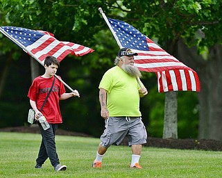 Jeff Lange | The Vindicator  MAY 25, 2015 - Army Vietnam veteran Thomas Moenich of Boardman and his grandson Samuel Arnold carry American flags as they make their way to Maag Outdoor Arts Theatre in Boardman Park, Monday morning during the Memorial Day celebration in Boardman.