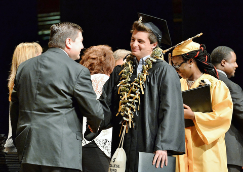 Jeff Lange | The Vindicator  MAY 28, 2015 - Darien Morgan (center) smiles as he walks across the stage with his diploma and college fund necklace during Thursday's commencement ceremony in Warren.