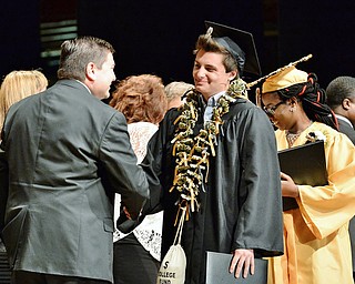 Jeff Lange | The Vindicator  MAY 28, 2015 - Darien Morgan (center) smiles as he walks across the stage with his diploma and college fund necklace during Thursday's commencement ceremony in Warren.