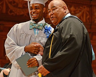 Katie Rickman | The Vindicator.Brandon Jackson smiles as he shakes hands with East High School Principal Tyvan Leech after receiving his diploma during the East High School commencement ceremony at Stambaugh Auditorium on June 5, 2015.