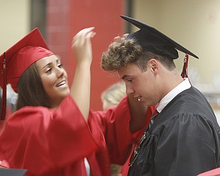       .         ROBERT  K. YOSAY | THE VINDICATOR..final adjustments as Allison Fabry positions the hat of Dylan Kuhn..Canfield High School Graduation on the football field in Canfield..-30-