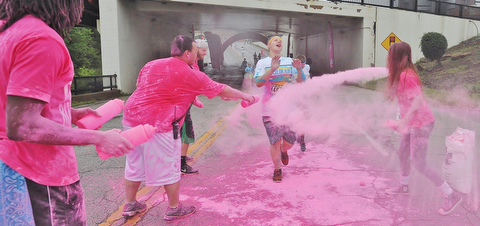 Jeff Lange | The Vindicator  JUNE 13, 2015 - A 2015 Youngstown Color Runner is coated with pink powder as he runs the final kilometer of the Color Run, downtown, Saturday morning.