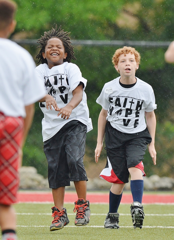 Jeff Lange | The Vindicator  JUNE 20, 2015 - 8 year old Noah Thomas (left) and 10 year old Peyton Quarles both of Austintown participate in warmup exercises prior to the start of Saturday's 8th annual Brad Smith football camp held at Stambaugh Stadium in Youngstown.