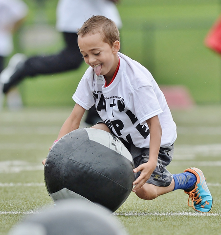 Jeff Lange | The Vindicator  JUNE 20, 2015 - 8 year old Isaac Lamorticella of Springfield sticks his tongue out as he picks up a medicine ball during drills at the 8th annual Brad Smith football camp held at Stambaugh Stadium in Youngstown, Saturday morning.