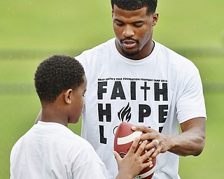 Jeff Lange | The Vindicator  JUNE 20, 2015 - Youngstown native and wide receiver in the NFL Brad Smith (right) assists 10 year old Benjaylin Hawkins of Youngstown in gripping the ball during quarterback drills at the 8th annual Brad Smith football camp held at Stambaugh Stadium in Youngstown, Saturday morning.