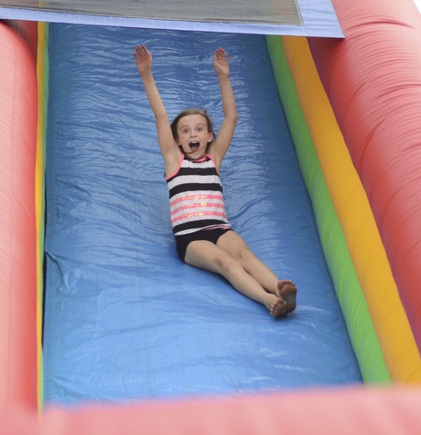 Katie Rickman | The Vindicator.Ava Ekis 8 of Austintown throws her hands in the air as she excitedly slides down a bounce house slide at the Austintown Fireworks Celebration July 3, 2015.