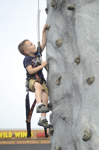 Katie Rickman | The Vindicator.Ethan Dean 4 of McDonald climbs up the rock wall at the Austintown Fireworks Celebration July 3, 2015.