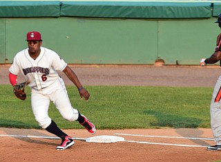 NILES, OHIO - JULY 4, 2015: First basemen Emmanuel Tapia #6 of the Scrappers watches as the baseball goes past him and into right field after a wild throw from the catcher, while base runner Randy Gassaway #14 reaches first base in the 2nd inning of Saturday nights game at Eastwood Field. DAVID DERMER | THE VINDICATOR