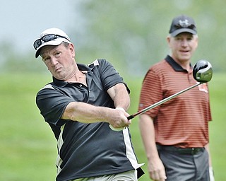 Jeff Lange | The Vindicator  JULY 6, 2015 - Brian Girts of Poland drives the ball as teammate Joel Smith of Cuyahoga Falls looks on from behind during Monday's Magic of Michael Foundation golf outing held at the Lake Club in Poland.
