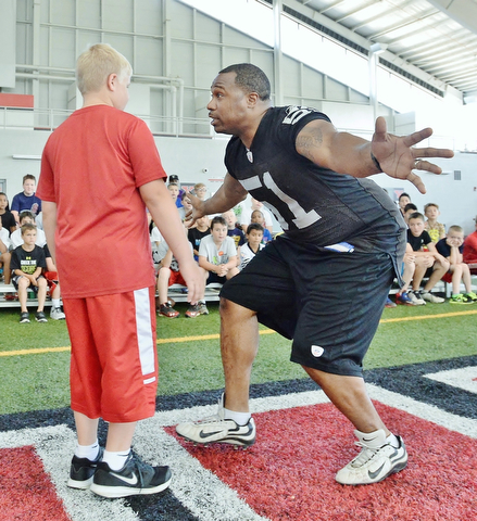 Jeff Lange | The Vindicator  JULY 11, 2015 - Former NFL linebacker Tim Johnson (right) pretends to tackle 11 year old Josh Burgoy of Poland during a demonstration before the start of Johnson's annual football camp at the WATTS center in Youngstown Saturday morning.