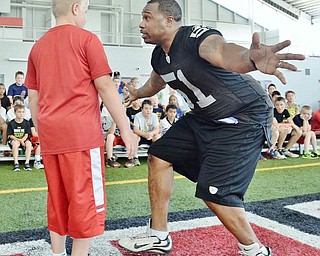Jeff Lange | The Vindicator  JULY 11, 2015 - Former NFL linebacker Tim Johnson (right) pretends to tackle 11 year old Josh Burgoy of Poland during a demonstration before the start of Johnson's annual football camp at the WATTS center in Youngstown Saturday morning.