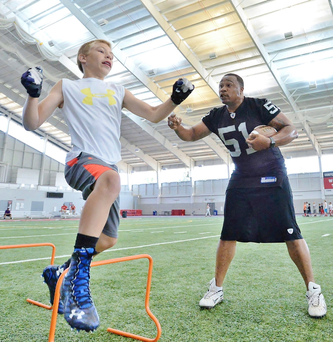 Jeff Lange | The Vindicator  JULY 11, 2015 - Former NFL linebacker Tim Johnson (right) encourages 12 year old Daniel Adams of Poland during drills at the WATTS center in Youngstown during Johnson's annual football camp, Saturday morning.