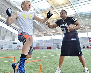 Jeff Lange | The Vindicator  JULY 11, 2015 - Former NFL linebacker Tim Johnson (right) encourages 12 year old Daniel Adams of Poland during drills at the WATTS center in Youngstown during Johnson's annual football camp, Saturday morning.