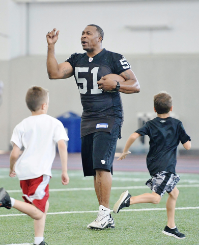 Jeff Lange | The Vindicator  JULY 11, 2015 - Former NFL player and YSU grad Tim Johnson (center) motivates young football players during his annual football skills camp at the WATTS center in Youngstown, Saturday morning.