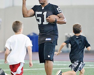 Jeff Lange | The Vindicator  JULY 11, 2015 - Former NFL player and YSU grad Tim Johnson (center) motivates young football players during his annual football skills camp at the WATTS center in Youngstown, Saturday morning.
