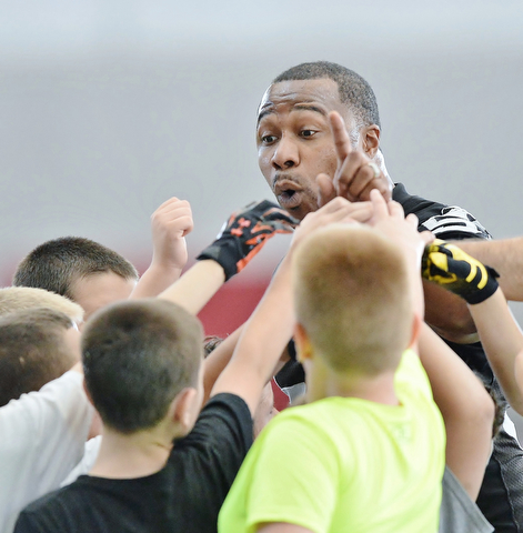 Jeff Lange | The Vindicator  JULY 11, 2015 - Former NFL player and YSU grad Tim Johnson (facing) huddles up with children in between drills at his football skills camp at YSU Saturday morning.