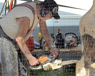 Katie Rickman | The Vindicator.Rick Cox of R & S Woodcarving works on a wooden statue near his camper at the Trumbull County Fairgrounds on various rides Saturday, July 18, 2015.