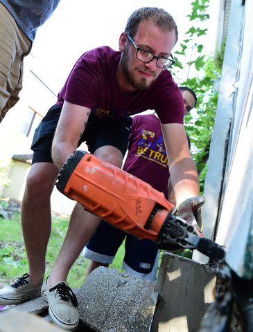 YOUNGSTOWN, OHIO - JULY 25, 2015: Matt Scott of Boardman nails a board to the doorframe of an abandoned home on Park Avenue Saturday morning during a YSU Wick Park neighborhood clean up. DAVID DERMER | THE VINDICATOR