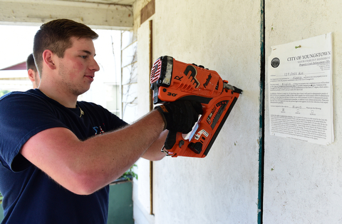 YOUNGSTOWN, OHIO - JULY 25, 2015: Nick Diloreto of East Liverpool nails a board to the doorframe of an abandoned home on Park Avenue Saturday morning during a YSU Wick Park neighborhood clean up. DAVID DERMER | THE VINDICATOR