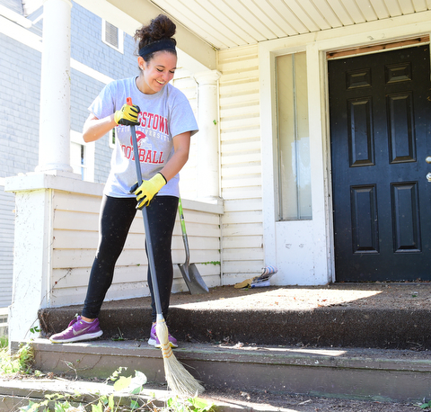 YOUNGSTOWN, OHIO - JULY 25, 2015: Gianna Marinucci of Boardman sweeps away weeds and small debris outside of an abandoned home on Park Avenue Saturday morning during a YSU Wick Park neighborhood clean up. DAVID DERMER | THE VINDICATOR