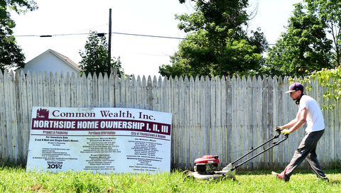YOUNGSTOWN, OHIO - JULY 25, 2015: Dylan Ingram of Boardman mows the grass outside of an abandoned home on Park Avenue Saturday morning during a YSU Wick Park neighborhood clean up. DAVID DERMER | THE VINDICATOR