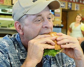 Jeff Lange | The Vindicator  JULY 22, 2015 - JT Tranovich of the Burger Guyz bites down on his Bacon Angus Cheeseburger, Wednesday night at Four Star Diner in Cortland.