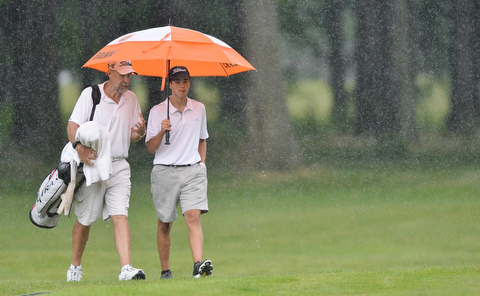 Jeff Lange | The Vindicator  JULY 26, 2015 - Anthony Granziano of Girard (right) and personal coach John Perry of Houston, Texas walk the course in a downpour during Sunday afternoon's Greatest Golfer of the Valley Junior championship held at Avalon Lakes Golf & Country Club in Howland.
