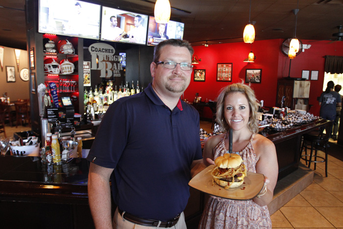 The owners of COACHES Burger Bar, Patrick Howlett and  Stacy Sam, posed with the burger of the month: the Big Texan