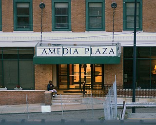 A person sits on the front stoop of the Amedia Plaza apartments on Hazel Street.