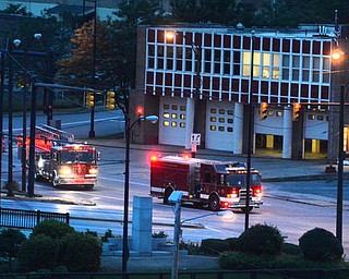 The city skyline shines bright with lights as the sun goes down, the lights cast a yellow glow.