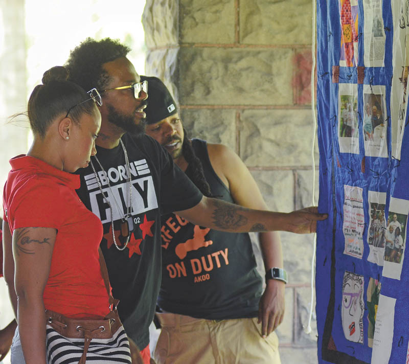 Katie Rickman | The Vindicator: The Sharper siblings of Youngstown, from left, Keisha, Bryan and Davon, look at a quilt containing family photos from the many years of the Cyrus-Ormes-Manzilla Annual Reunion.