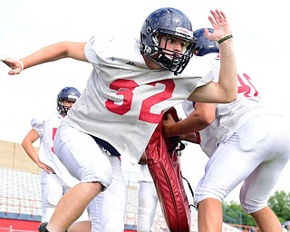 AUSTINTOWN, OHIO - AUGUST 11, 2015: Brett Moyer #32 of Fitch rips though a bag being held by Tommy Ellsmore #40 during a linebackers drill Tuesday morning during a preseason practice at Fitch High School. DAVID DERMER | THE VINDICATOR