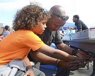 Katie Rickman | The Vindicator.Deputy Art Thompson, on right, completes a finger print identification procedure on 8-year-old Judah Leonard during the community wide back-to-school backpack giveaway at the Covelli Centre August 24, 2015.