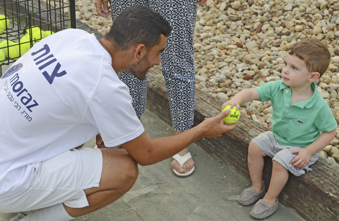 Katie Rickman | The Vindicator. Yossi Dahan 18 of Ramat Hasharon on left hands a tennis ball to one-year-old Levi Kessler of New York City after Dahan took part in the Israeli Tennis Center exhibition at Youngstown Country Club August 24, 2015.
