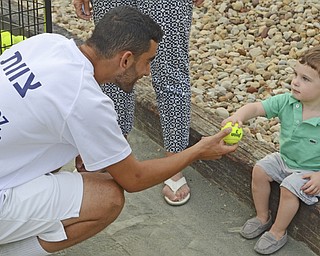 Katie Rickman | The Vindicator. Yossi Dahan 18 of Ramat Hasharon on left hands a tennis ball to one-year-old Levi Kessler of New York City after Dahan took part in the Israeli Tennis Center exhibition at Youngstown Country Club August 24, 2015.