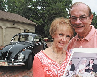 
Poland residents Tom and Mary Jane Hall are holding a picture of themselves on their wedding day Sept. 11, 1965. Behind them is the Volkswagen Beetle they purchased that same year. Despite its 50 years on the road, the vintage car has most of its original parts, including an odometer with a mere 57,713 miles on it. Photo by William D. Lewis | The Vindicator 