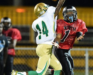 YOUNGSTOWN, OHIO - AUGUST 28, 2015: Imoni Donadelle #1 of East reaches for the football while Dakota Hobba #14 of Ursuline interferes with him during the 2nd half of a game Friday night at Rayen Stadium. DAVID DERMER | THE VINDICATOR