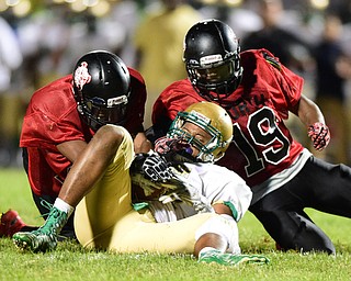 YOUNGSTOWN, OHIO - AUGUST 28, 2015: Linebacker Jabbar Price #52 of Ursuline gains control of the football while Leon Bell #19 and Mike Stevens #17 of East attempt to get the ball back during the 2nd half of a game Friday night at Rayen Stadium. DAVID DERMER | THE VINDICATOR
