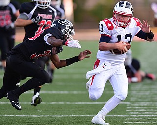 GIRARD, OHIO - AUGUST 27, 2015: Quarterback Tyler Srbinovich #13 of Niles runs the football upfield before being forced out of bounds by defensive back Colin Harden #39 of Girard during the 1st half of their football game Thursday night at Arrowhead Stadium. DAVID DERMER | THE VINDICATOR