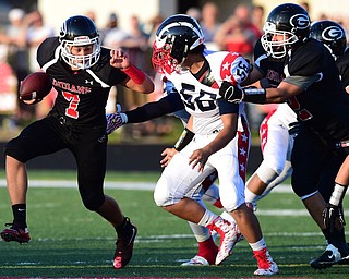 GIRARD, OHIO - AUGUST 27, 2015: Quarterback Mark Waid #7 of Girard runs with he football while Joe Lewis #56 of Niles goes for the tackle while being held by Ben Norman #72 during the 1st half of their football game Thursday night at Arrowhead Stadium. DAVID DERMER | THE VINDICATOR