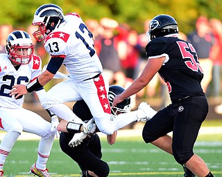 GIRARD, OHIO - AUGUST 27, 2015: Quarterback Tyler Srbinovich #13 of Niles attempts to jump over defensive back Tyler O'Dell #15 of Girard before being brought down by Nate Marlin #53 during the 1st half of their football game Thursday night at Arrowhead Stadium. DAVID DERMER | THE VINDICATOR