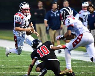 GIRARD, OHIO - AUGUST 27, 2015: Quarterback Tyler Srbinovich #13 of Niles runs down the sideline after picking up a block from Marlon Pearson #2 on Nick Hall #10 of Girard during the 1st half of their football game Thursday night at Arrowhead Stadium. DAVID DERMER | THE VINDICATOR